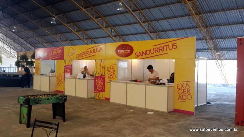 Fileira de stands de alimentação com balcão e testeira em festival