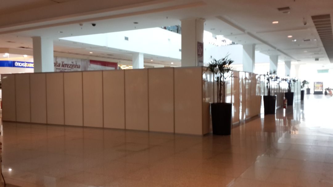Tapume branco com painéis modulares fechando loja em obra em shopping