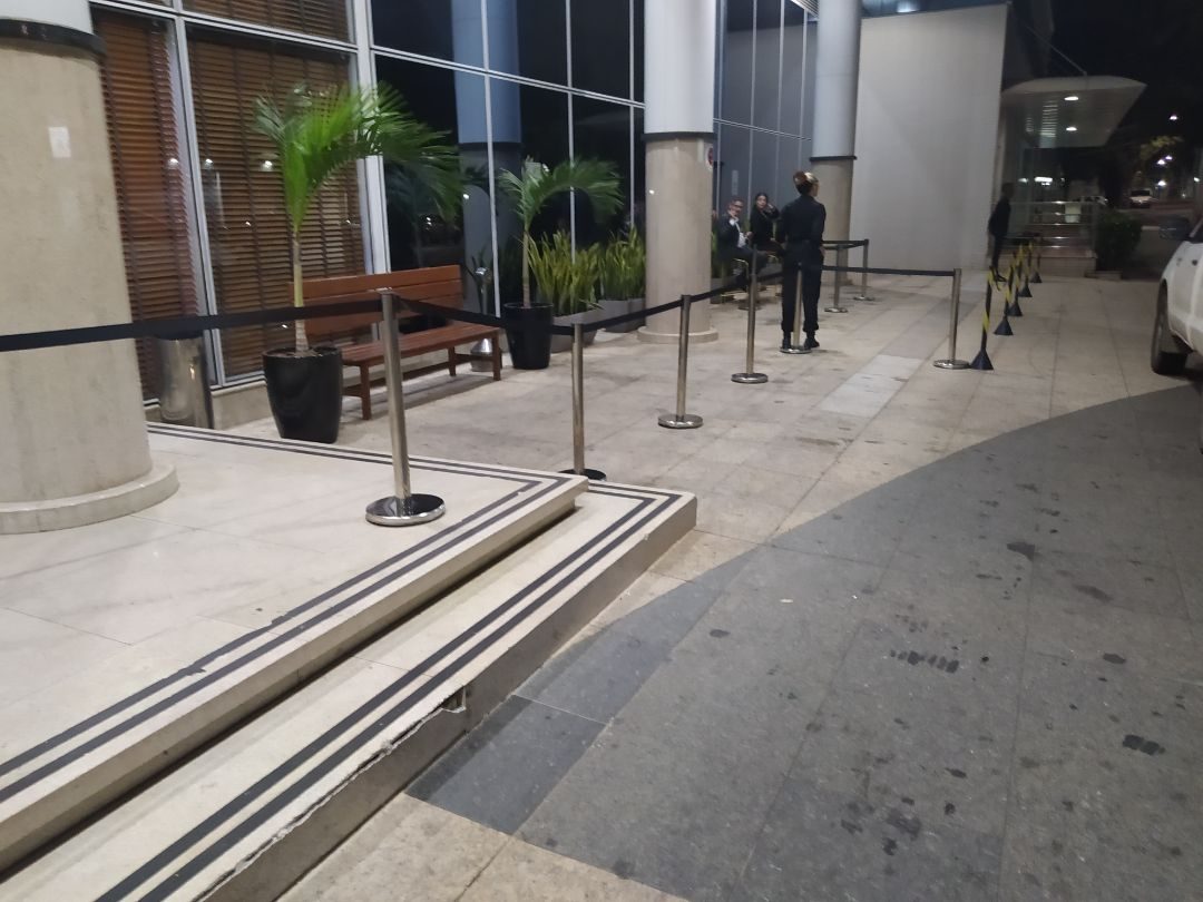 Pedestais cromados com fita retrátil preta organizando fila em evento